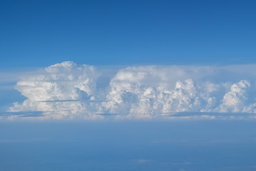 Large cloud and blue sky seen from aircraft flying in cruise altitude