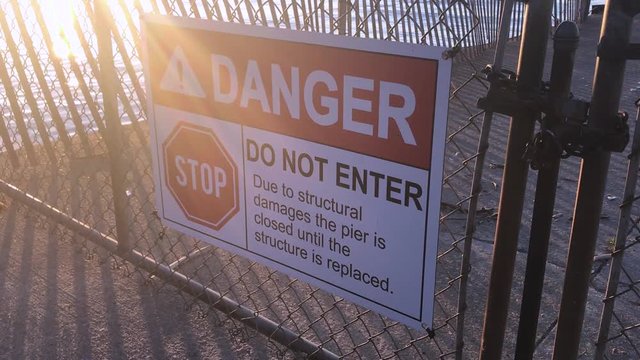 Pier closed signs of danger where a beach is not safe and falling into disrepair. Danger beach with a broken fishing pier.
