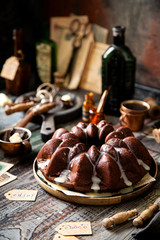 Delicious homemade chocolate bundt cake on wooden plate stands on rustic table