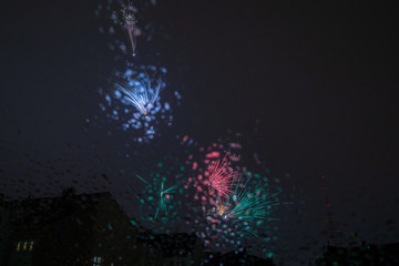New years eve fireworks seen trough a roof window pane full of raindrops