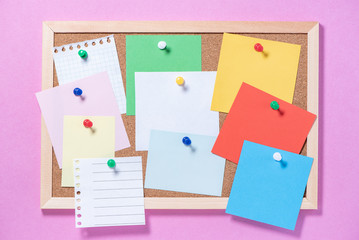Corkboard for notes with empty sheets on buttons on a pink background