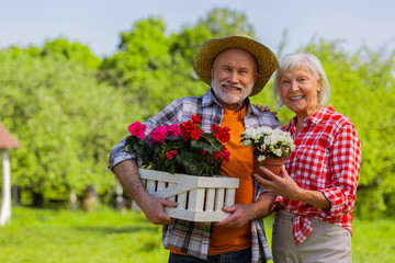 Husband and wife smiling broadly standing with flower pots