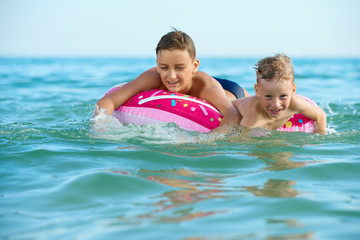 Fototapeta na wymiar TWO BOYS SAVE ON A INFLATABLE CIRCLE AT SEA