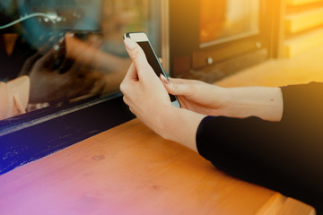 Girl waiting coffee in the street coffee shop and surfing the net with smartphone