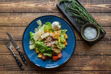 The hot salad with meat on a wooden background.