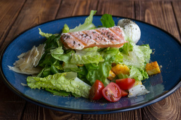 The salad with salmon on a wooden table.