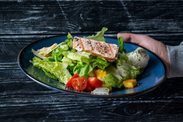 The salad with salmon on a wooden table.