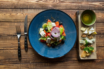 Greek salad in a plate on a wooden table.
