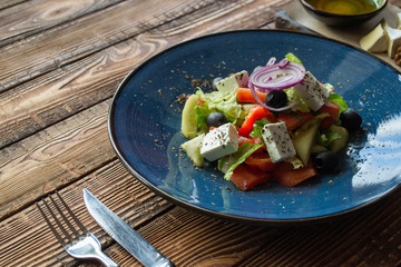 Greek salad in a plate on a wooden table.