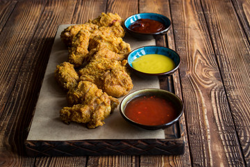 Fried chicken with sauce on a wooden table.