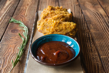 Fried chicken with sauce on a wooden table.
