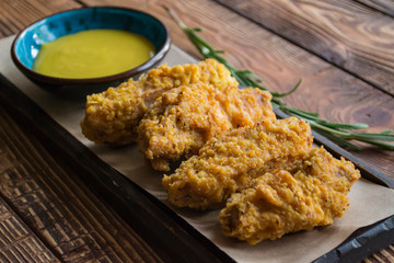 Fried chicken with sauce on a wooden table.
