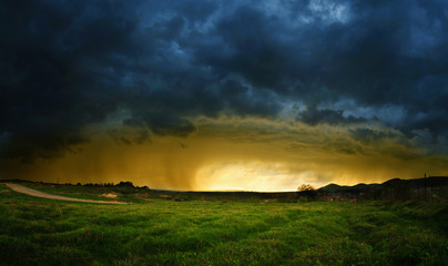 Naklejka na ściany i meble Very intense storm scene with rain on the left side and sunlight at the horizon