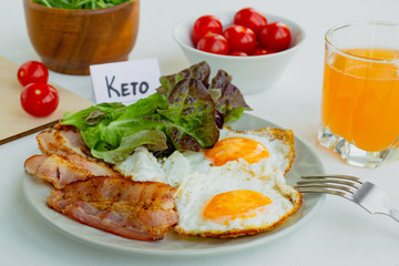 Ketogenic diet food. Fried eggs, bacon and lettuce on a plate. Keto diet concept