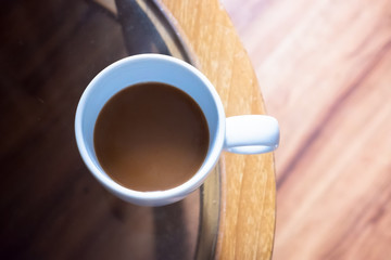 Top view of one cup hot coffee with smoke on the glass table in the window light in room