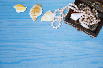 Wooden chest with shells and beads on wooden background.