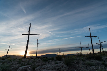 Silhouettes of crosses made with trunks under a sunset sky