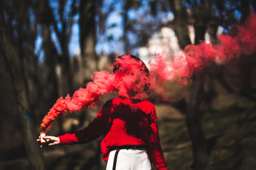 Beautiful woman in red smoke grenade standing in the street