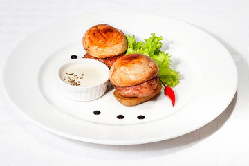 Dish of pork medallions on white background