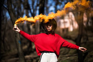 Girl holding a orange smoke bomb in the park