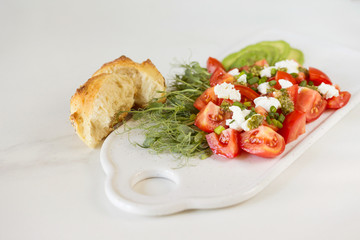 Breakfast salad with tomatoes, avocado, bun, pea sprouts, and coffee