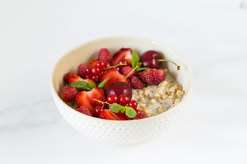 Fresh oatmeal breakfast with milk and berry