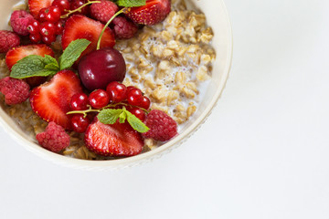 Fresh oatmeal breakfast with milk and berry
