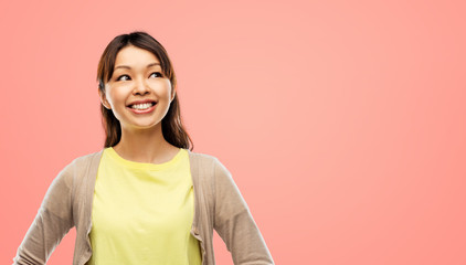 people, ethnicity and portrait concept - happy asian young woman looking up over pink living coral...