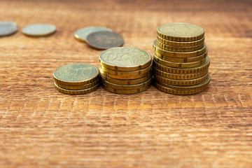 Staked coins growing, increase, changing euro pile pack heap on a wooden background mock up selective focus close up