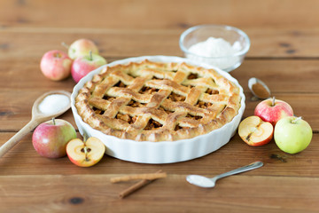 food, culinary and pastry concept - close up of apple pie with cinnamon and sugar on wooden table