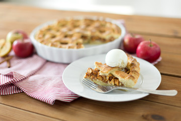 food, culinary and baking concept - piece of apple pie with ice cream on plate with fork