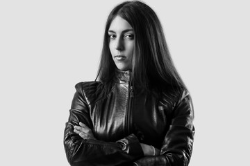 Studio portrait of a young woman with long brown hair wearing a black leather jacket 