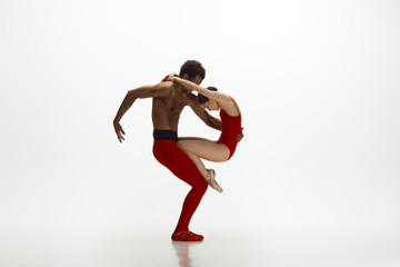 Graceful classic ballet dancers dancing isolated on white studio background. Couple in bright red...