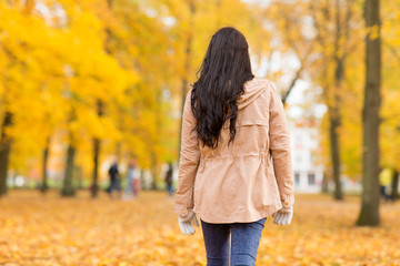 season and people concept - young woman walking in autumn park