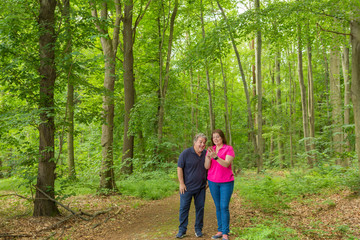 Couple Enjoying the walk in the forest and watch some content on her smartphone