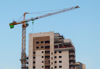 Construction crane building a house against a blue sky