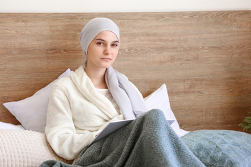 Woman after chemotherapy reading book in bedroom