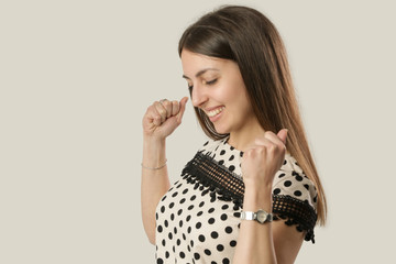 A powerful young woman in polka dots shirt on a grey background, studio shot of joyful very happy girl