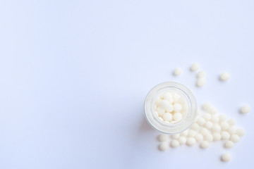 Close up homeopathic globules and glass bottle on blue background. Alternative Homeopathy medicine herbs, healtcare and pills concept. Flatlay. Top view. copyspace for text