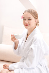 Beautiful young woman drinking coffee in spa salon