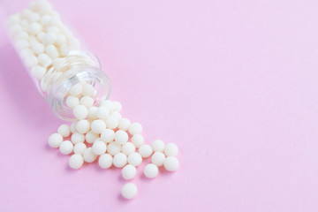 homeopathic globules and glass bottle on pink background. Alternative Homeopathy medicine herbs, healtcare and pills concept. Flatlay. Top view. copyspace for text