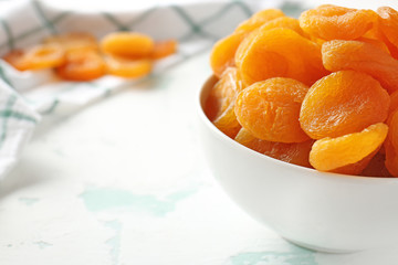 Bowl with dried apricots on light background, closeup