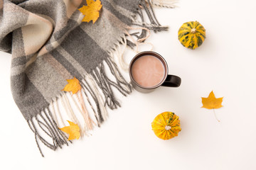 drinks and season concept - cup of hot chocolate, autumn leaves, pumpkins and warm blanket on white background