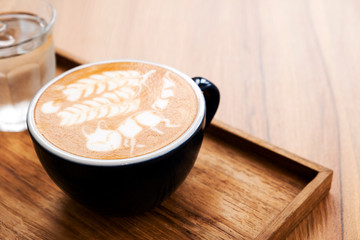 Hot latte with beautiful latte art on the wooden table