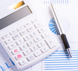 White calculator and report with chart and graph, concept of annual financial profit overview, banking and investment, copy space, macro, close up