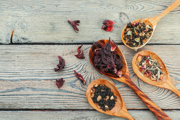 Black tea with herbs in wooden spoons on a wooden board