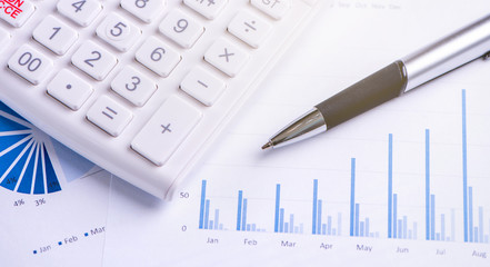 White calculator and report with chart and graph, concept of annual financial profit overview,...