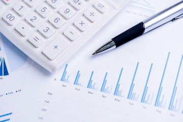 White calculator and report with chart and graph, concept of annual financial profit overview, banking and investment, copy space, macro, close up