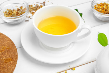 Cup of tea and tea leaves on white wooden table. close up.
