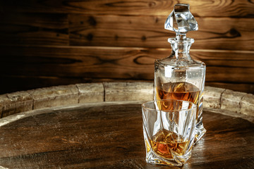 A bottle of cognac and glass on a brown wooden background. Brandy